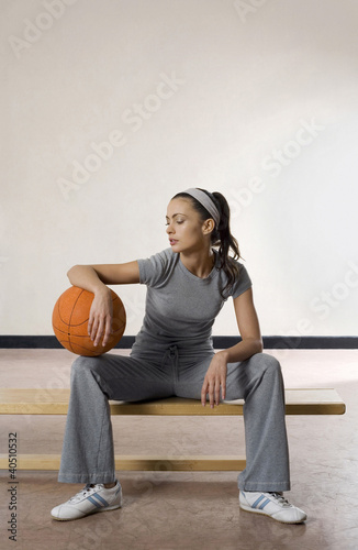 Photo: Woman sitting on bench with a basketball Woman sitting on bench with a basketball