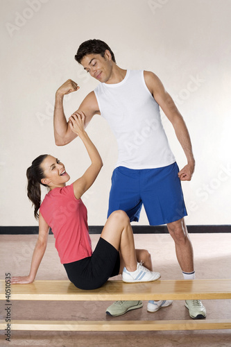 Photo: Man flexing his muscle, woman winking while touching his muscle Man flexing his muscle, woman winking while touching his muscle