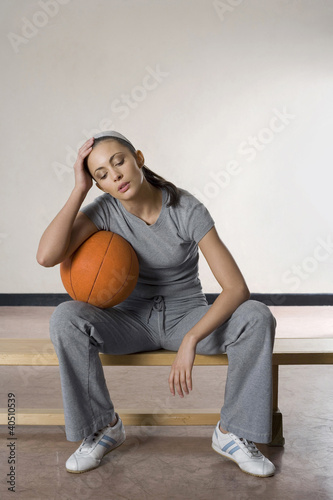 Photo: Woman sitting on bench with a basketball Woman sitting on bench with a basketball