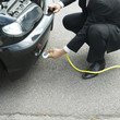 Businessman hooking the belt lift from tow truck to his car