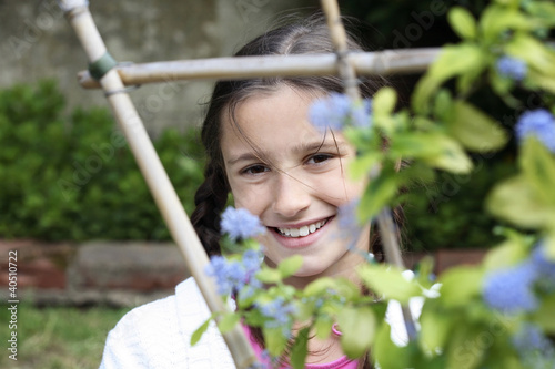 Photo: Girl looking through wooden post with flowers Girl looking through wooden post with flowers