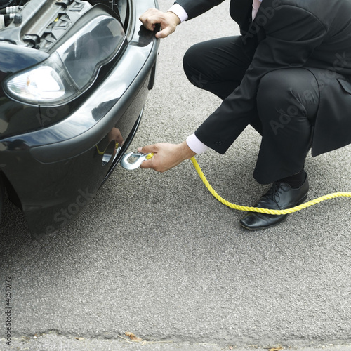 Photo: Businessman hooking the belt lift from tow truck to his car Businessman hooking the belt lift from tow truck to his car