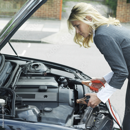 Photo: Businesswoman using jumper cables Businesswoman using jumper cables