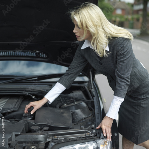Photo: Businesswoman looking under car hood Businesswoman looking under car hood