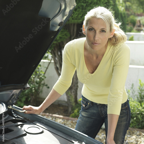 Photo: Woman with lug wrench looking under car hood Woman with lug wrench looking under car hood