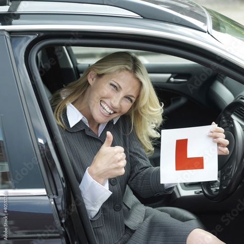 Photo: Businesswoman showing thumbs up while holding L plate Businesswoman showing thumbs up while holding L plate