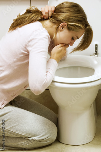 Photo: Girl vomiting into toilet bowl Girl vomiting into toilet bowl