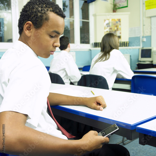 Foto: Boy text messaging in the classroom Boy text messaging in the classroom