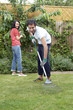 Man using the rake while woman is trimming the plants