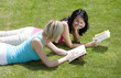 Two women lying forward in the park reading books