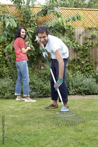 Photo: Man using the rake while woman is trimming the plants Man using the rake while woman is trimming the plants