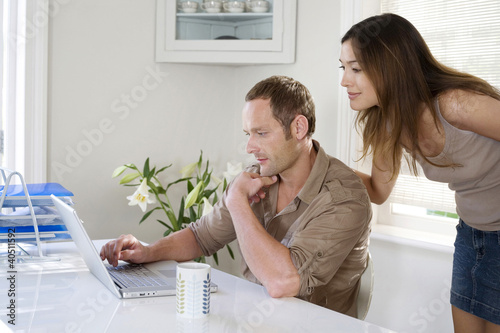 Photo: Woman watching man work in a home office Woman watching man work in a home office