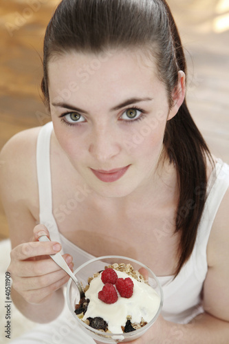 Photo: Woman holding a bowl of breakfast cereal with raspberries Woman holding a bowl of breakfast cereal with raspberries