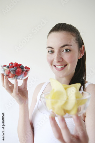 Photo: Woman holding a bowl of berries and chips in each hand Woman holding a bowl of berries and chips in each hand
