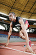 Foto: Man in starting position on running track Man in starting position on running track