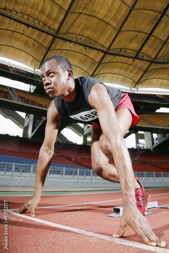 Photo: Man in starting position on running track Man in starting position on running track