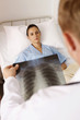 Doctor looking at X-ray image, patient lying on the bed