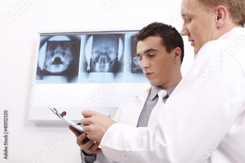 Photo: Doctors discussing while looking at papers on clipboard Doctors discussing while looking at papers on clipboard