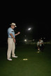 Two men playing golf at night