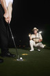 Two men playing golf at night