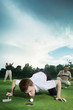 Man trying to blow golf ball into the hole with friends watching in the background