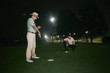 Two men playing golf at night