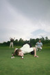 Foto: Man trying to blow golf ball into the hole with friends watching in the background Man trying to blow golf ball into the hole with friends watching in the background