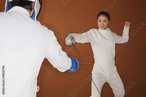 Photo: Woman with fencing foil dodging her opponent's attack Woman with fencing foil dodging her opponent's attack