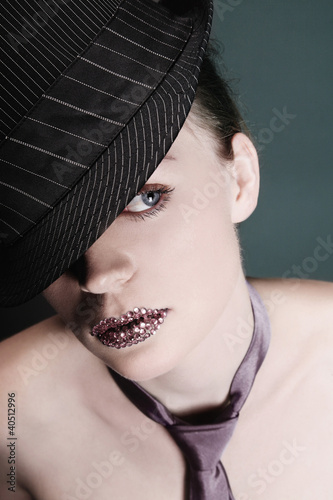 Foto: Woman with rhinestones on her lips wearing hat and necktie Woman with rhinestones on her lips wearing hat and necktie