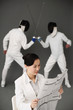 Businesswoman reading newspaper with two men fencing in the background