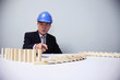 Businessman with safety helmet pointing at wooden blocks on the table