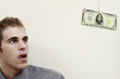 Businessman looking at banknote on fishing hook, tongue sticking out