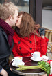 Happy couple kissing in Parisian cafe