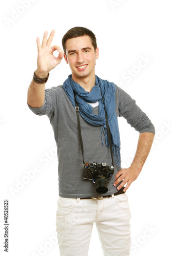 Photo: A tourist with camera shows a sign okay A tourist with camera shows a sign okay