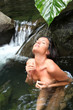 Beautiful girl showering in river under waterfall