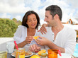 Cheerful couple taking breakfast on the outdoor terrace