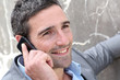 Businessman talking on mobile phone against wall