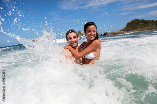 Photo: Cheerful couple enjoying the waves Cheerful couple enjoying the waves
