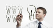 Business man drawing many small light bulbs equal a big one Business man drawing many small light bulbs equal a big one