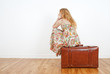 Girl sitting on a vintage suitcase anticipating travel
