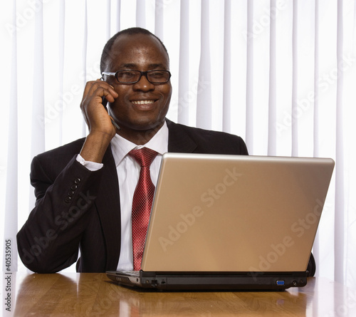 Photo: A black businessman working at his desk on a laptop A black businessman working at his desk on a laptop