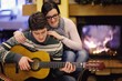 Young romantic couple sitting on sofa in front of fireplace at h