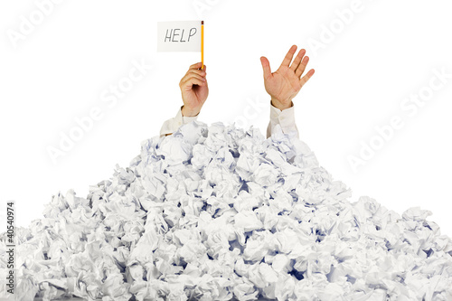 Photo: Person under crumpled pile of papers with hand holding a help si Person under crumpled pile of papers with hand holding a help si