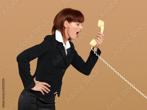 Photo: attractive, young businesswoman screaming into the telephone attractive, young businesswoman screaming into the telephone