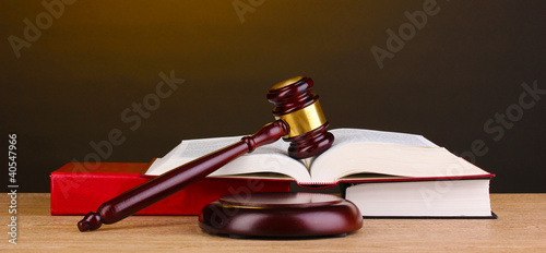 Foto: Judge's gavel and books on wooden table on brown background Judge's gavel and books on wooden table on brown background