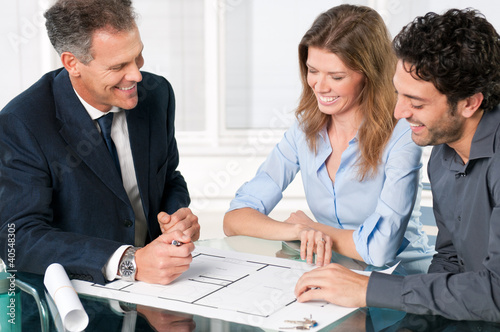 Photo: Estate agent with smiling couple Estate agent with smiling couple