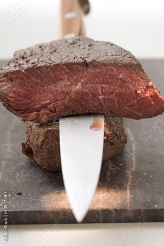 Foto: Beef steaks, one with a piece cut off, with knife Beef steaks, one with a piece cut off, with knife