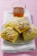 Four pieces of bee sting cake on plate in front of glass of honey