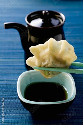 Foto: Pasta parcel on chopsticks above soy sauce Pasta parcel on chopsticks above soy sauce