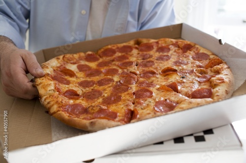 Photo: Man holding pizza box containing pepperoni pizza Man holding pizza box containing pepperoni pizza